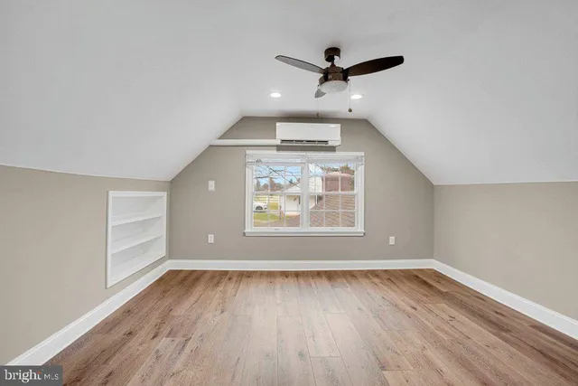 an empty room with wooden floor ceiling fan and windows