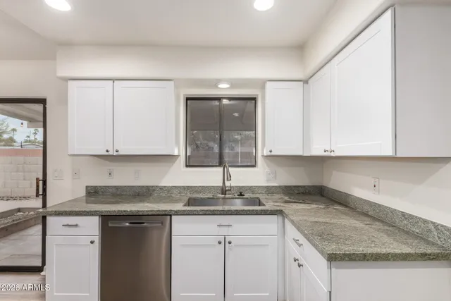 a view of a kitchen with a sink wooden cabinets and window