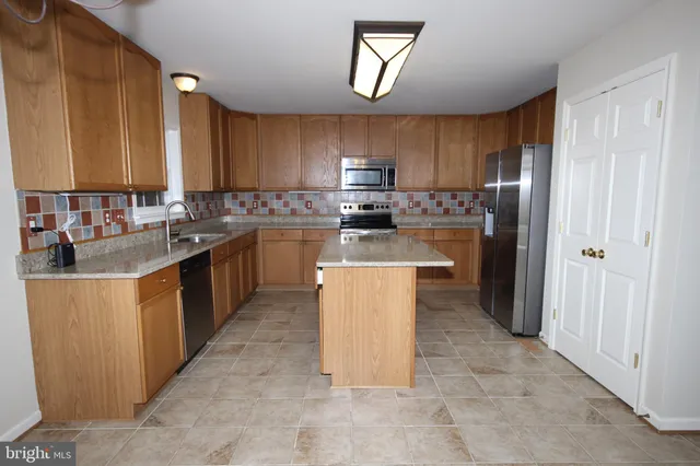 a kitchen with stainless steel appliances granite countertop a stove top oven a sink a refrigerator and a cabinets