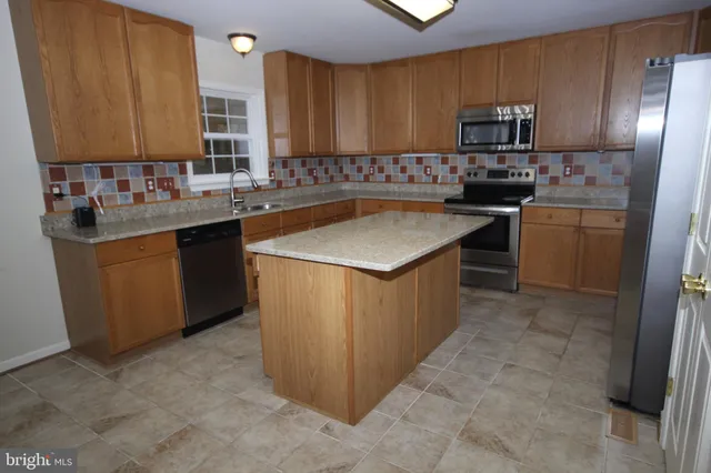 a kitchen with stainless steel appliances granite countertop a stove a sink dishwasher a refrigerator and a microwave oven