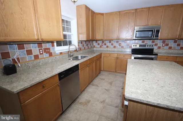 a kitchen with stainless steel appliances granite countertop a sink a stove top oven a counter space and cabinets