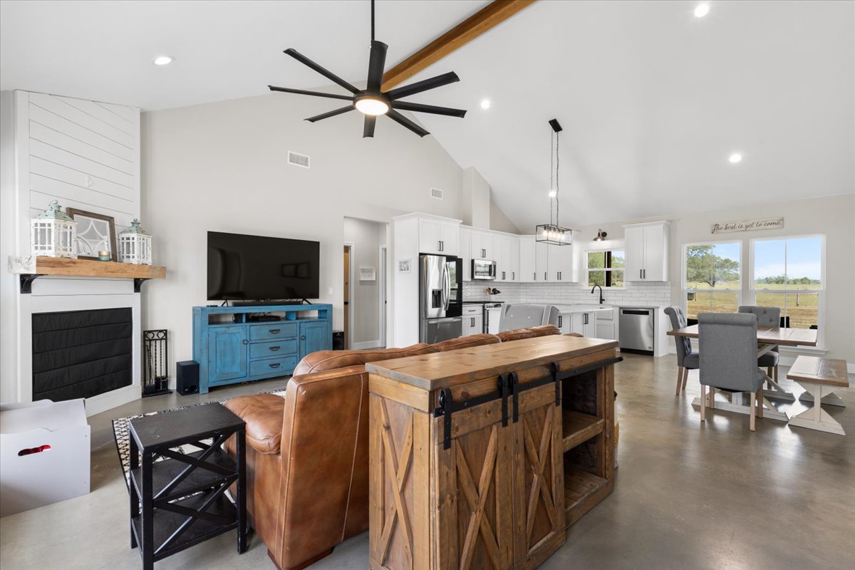 3389 Sparta Field Road Waelder, TX 78959 - Photo 5 of 40 Living room featuring ceiling fan, recessed lighting, finished concrete flooring, high vaulted ceiling, and a large fireplace