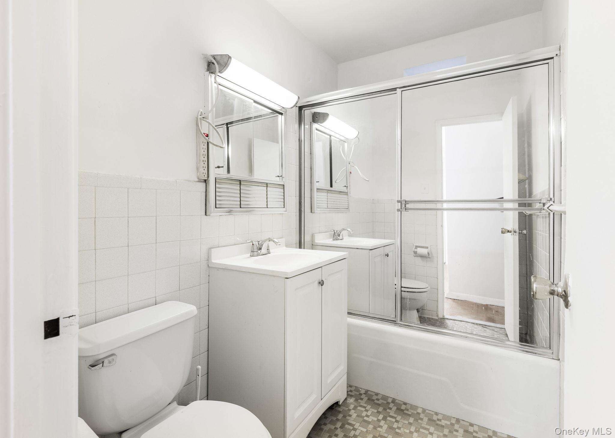 40 Brighton 1st Road, Unit 3J Brooklyn, NY 11235 - Photo 10 of 23 Full bathroom with vanity, enclosed tub / shower combo, tile walls, and toilet