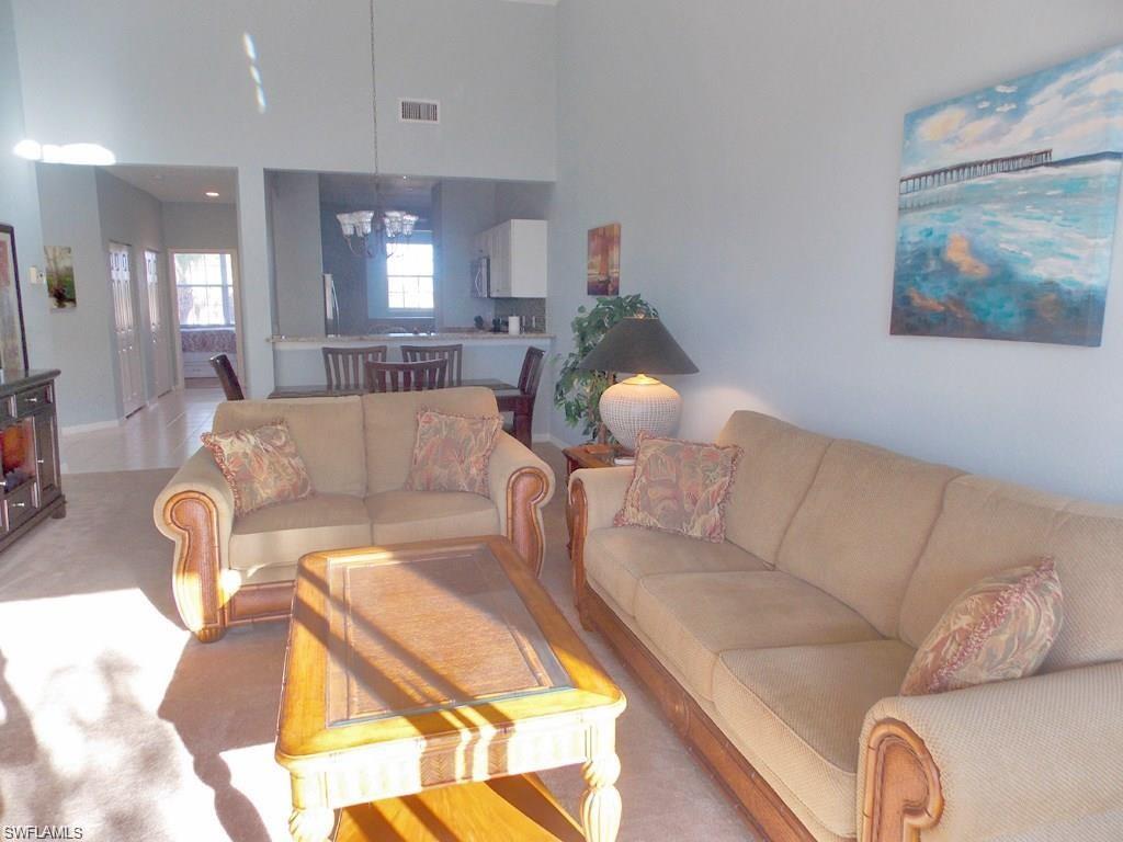 8365 Whisper Trace Way, Unit L203 Naples, FL 34114 - Photo 2 of 24 a living room with furniture and a chandelier