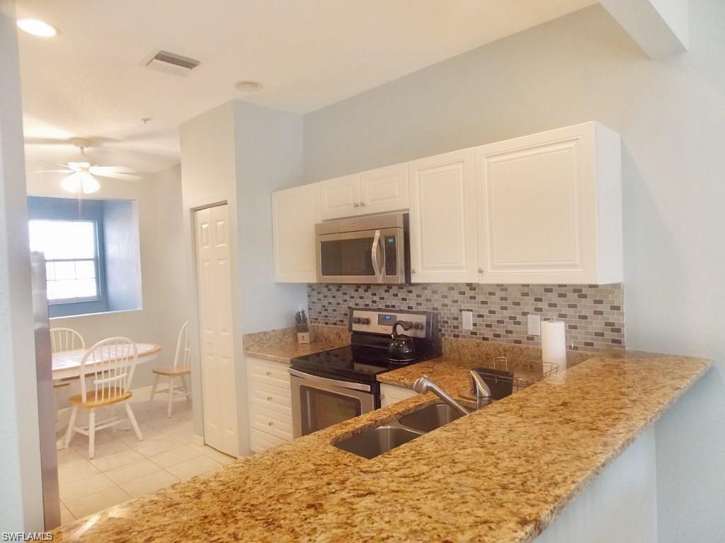8365 Whisper Trace Way, Unit L203 Naples, FL 34114 - Photo 7 of 24 a kitchen with stainless steel appliances kitchen island granite countertop a sink and a stove