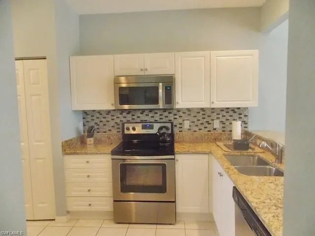 a kitchen with granite countertop a stove sink and cabinets