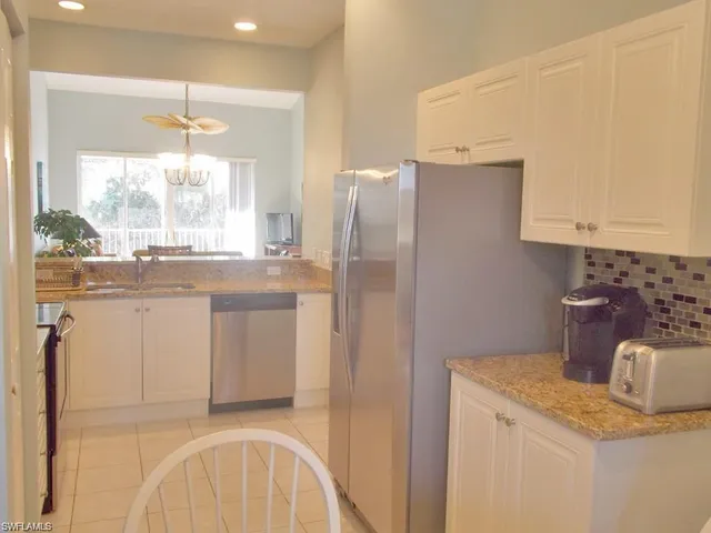 a kitchen with a refrigerator a stove a sink and white cabinets