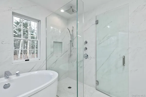 a bathroom with a bathtub a sink a window and a shower