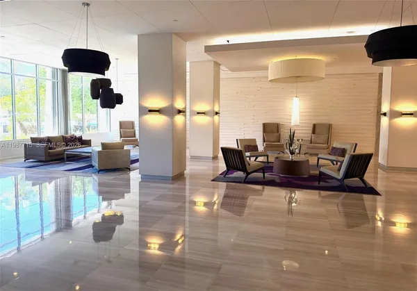 a view of a dining room with furniture a chandelier and large windows