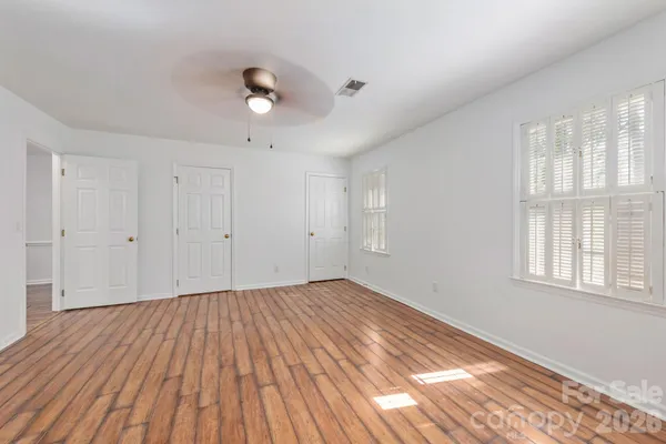 a view of empty room with wooden floor and fan