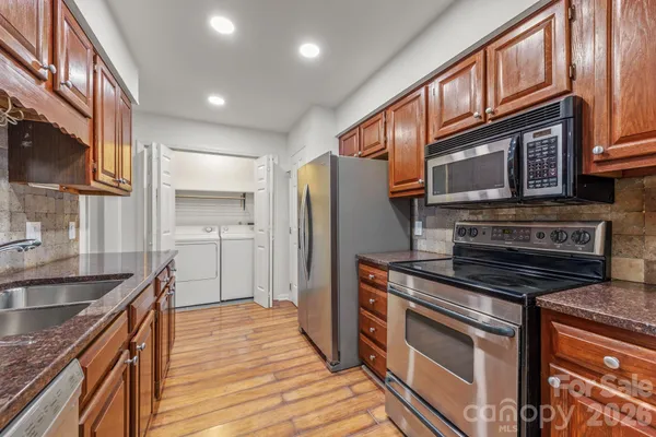a kitchen with stainless steel appliances granite countertop a stove a sink and a refrigerator