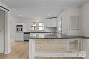 a kitchen with granite countertop white cabinets and a window