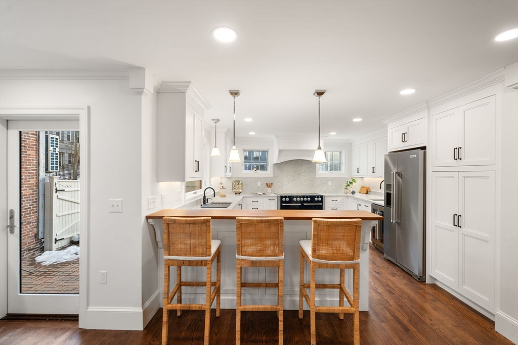 10 Bartlett Street Boston, MA 02129 - Photo 10 of 34 a kitchen with stainless steel appliances granite countertop a dining table chairs refrigerator and wooden floor
