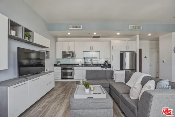 a living room with stainless steel appliances furniture and a flat screen tv