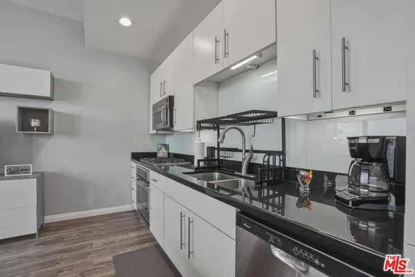 a kitchen with stainless steel appliances granite countertop a sink stove and cabinets