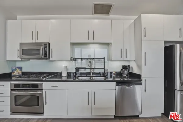 a kitchen with white cabinets and stainless steel appliances