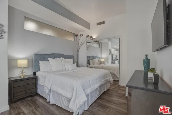 a bedroom with a bed and a flat tv screen on a dresser