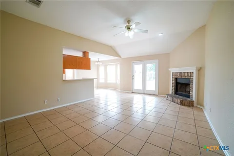 a view of an empty room with window and chandelier fan