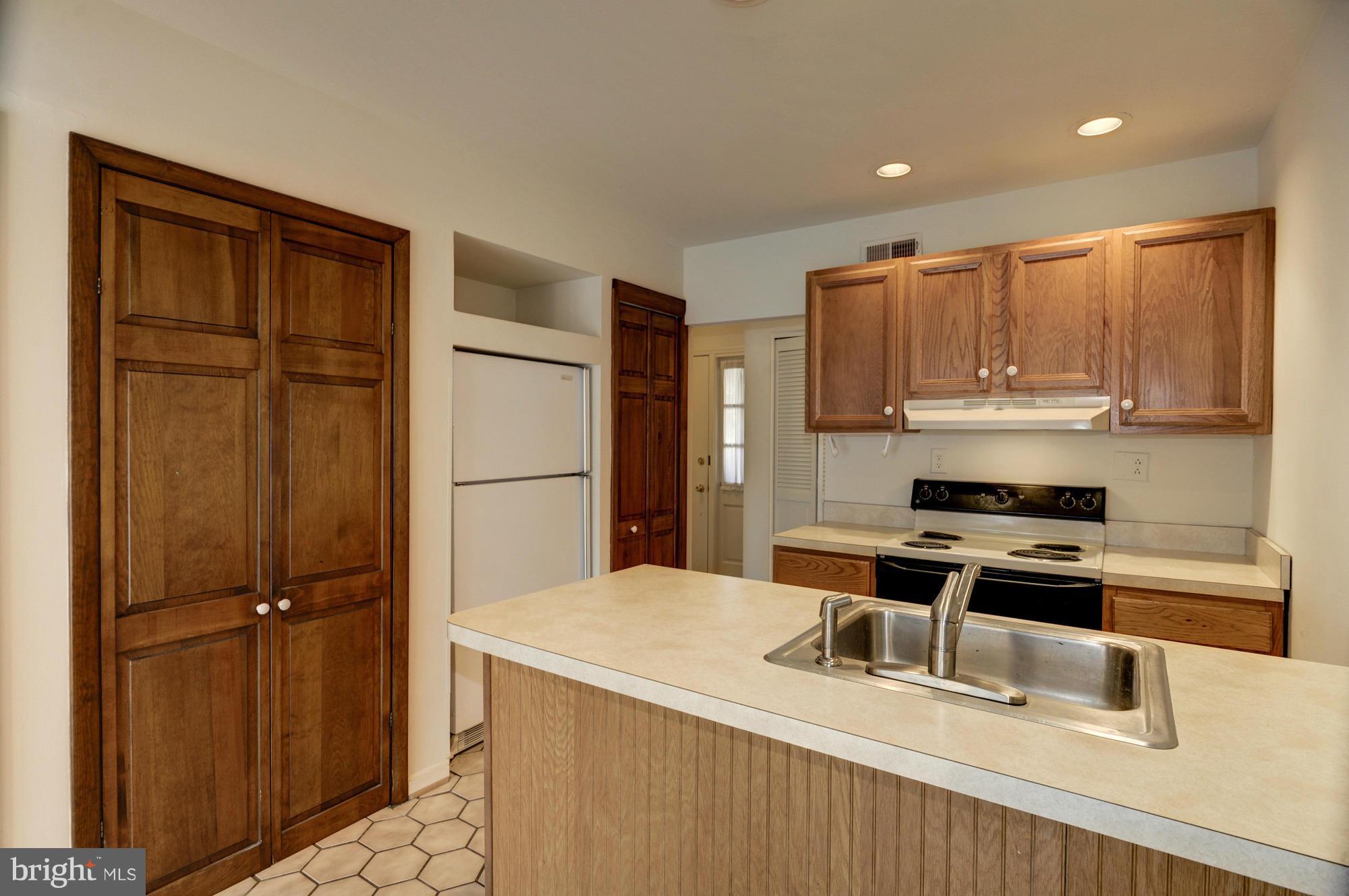 613 Edwards Road Annapolis, MD 21409 - Photo 8 of 28 a kitchen with a refrigerator a stove and a sink with wooden cabinets