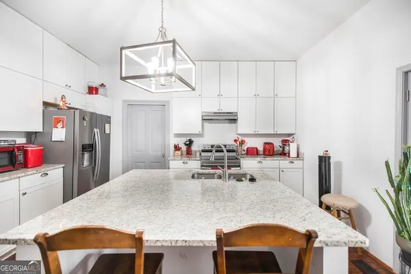a very nice looking dining room with kitchen island a stove a table and chairs