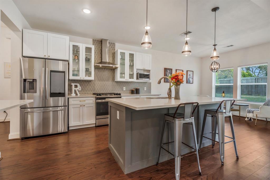 1909 Willowcrest Loop Denton, TX 76205 - Photo 11 of 40 Kitchen featuring decorative light fixtures, appliances with stainless steel finishes, glass insert cabinets, white cabinets, and wall chimney exhaust hood