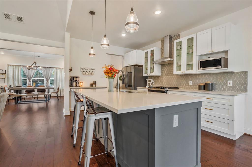 1909 Willowcrest Loop Denton, TX 76205 - Photo 12 of 40 Kitchen featuring decorative light fixtures, glass insert cabinets, white cabinetry, a breakfast bar, and recessed lighting