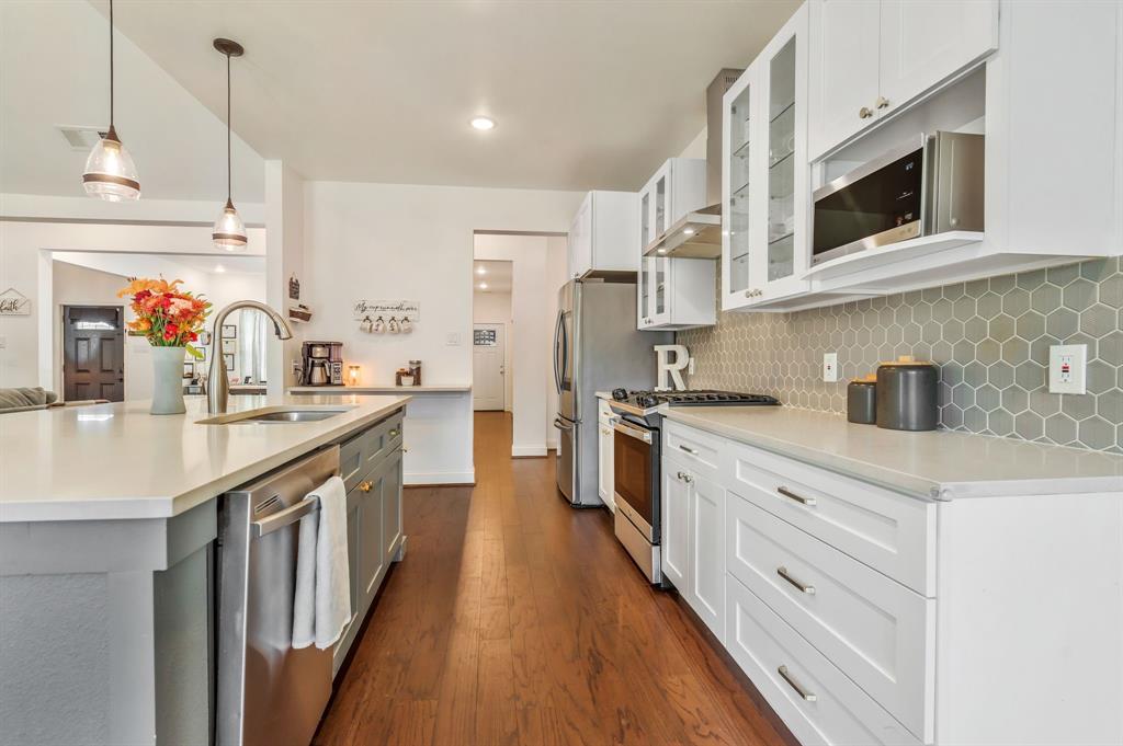 1909 Willowcrest Loop Denton, TX 76205 - Photo 13 of 40 Kitchen with white self close drawers and cabinets, appliances with stainless steel finishes, glass insert cabinets, and pendant lighting