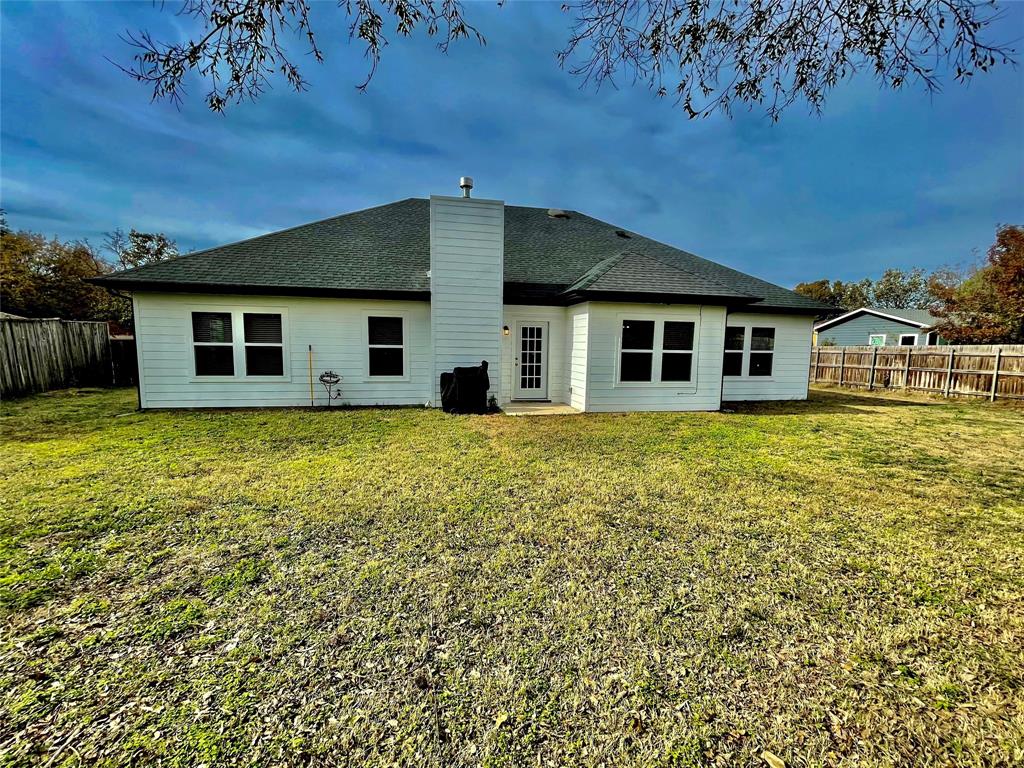 1909 Willowcrest Loop Denton, TX 76205 - Photo 33 of 40 Rear view of house featuring a fenced backyard, a shingled roof, a patio area, and a chimney