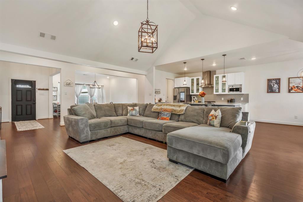 1909 Willowcrest Loop Denton, TX 76205 - Photo 10 of 40 Living room featuring dark wood-style flooring, high vaulted ceiling, and a chandelier