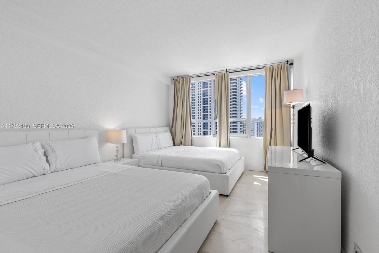 1500 Bay Road, Unit 1528S Miami Beach, FL 33139 - Photo 11 of 29 a bed room with bed and a flat tv screen on a dresser