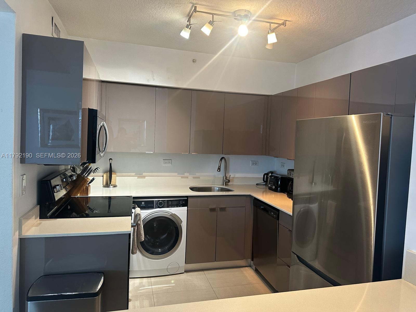 1500 Bay Road, Unit 1528S Miami Beach, FL 33139 - Photo 8 of 29 a kitchen with a sink a refrigerator and cabinets
