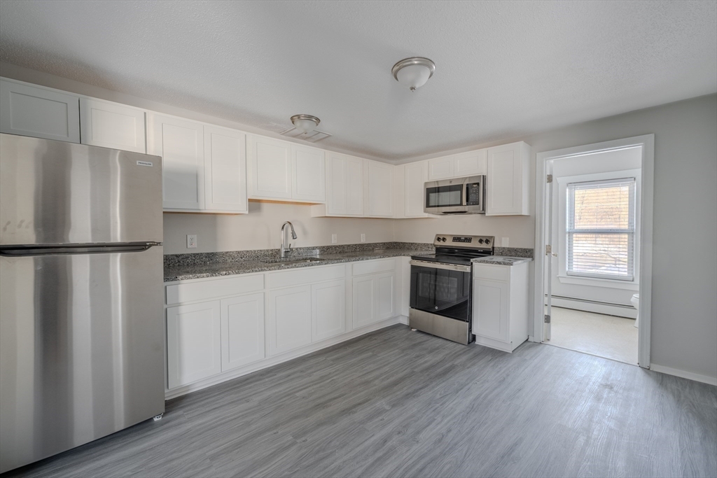 a kitchen with granite countertop white cabinets and stainless steel appliances