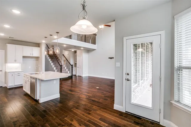 a view of a kitchen and an empty room with wooden floor