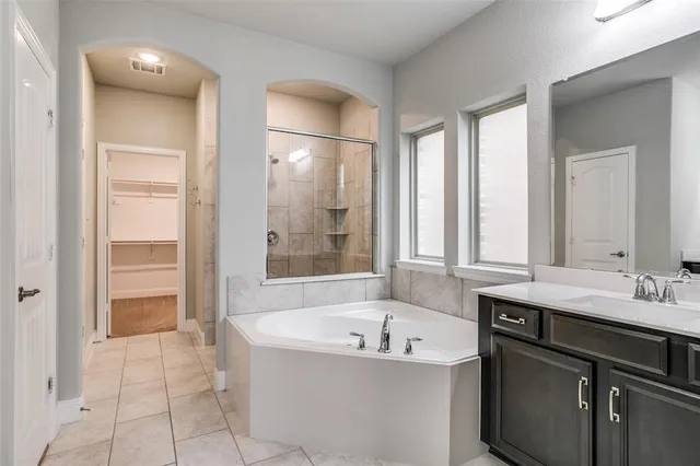 a spacious bathroom with a tub sink and mirror