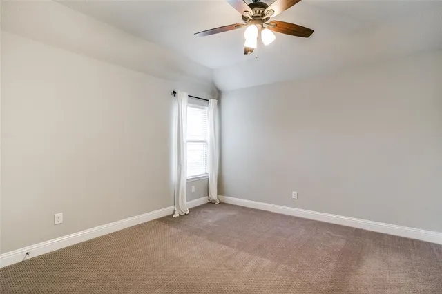 an empty room with a chandelier fan and windows
