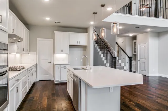 a kitchen with refrigerator a stove and wooden floor
