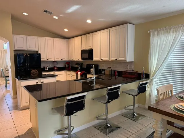 a kitchen with kitchen island granite countertop a stove a sink a refrigerator and cabinets