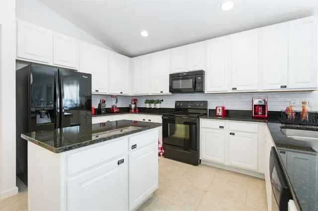 a kitchen with granite countertop a refrigerator stove top oven and sink