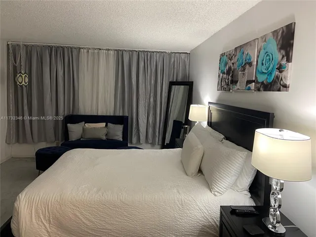 a bedroom with a bed and a flat tv screen on the dresser