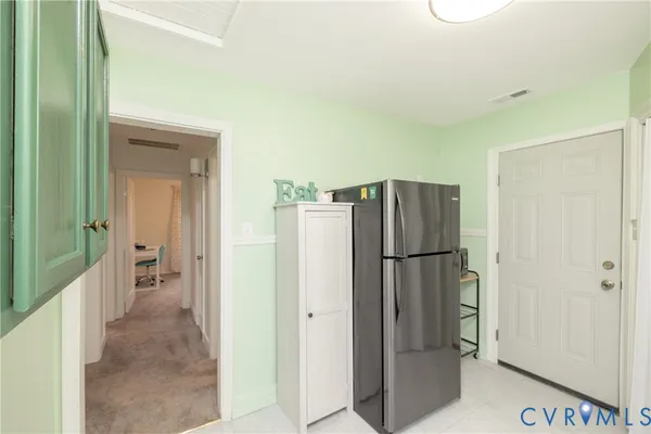 a view of kitchen with refrigerator cabinet and windows