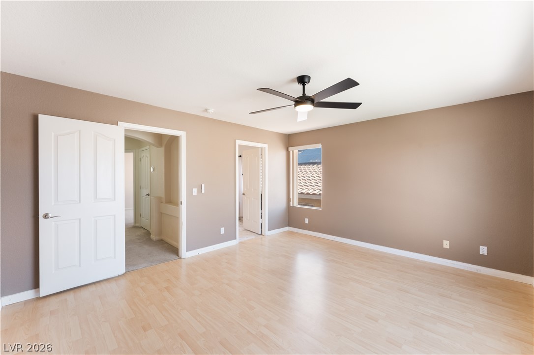 8872 Chapman Point Las Vegas, NV 89129 - Photo 15 of 29 Luminous Primary Bedroom featuring blonde wood flooring and an integrated ceiling fan for optimal comfort.