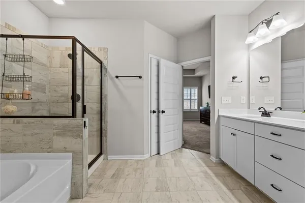 a spacious bathroom with a granite countertop sink a mirror and a bathtub