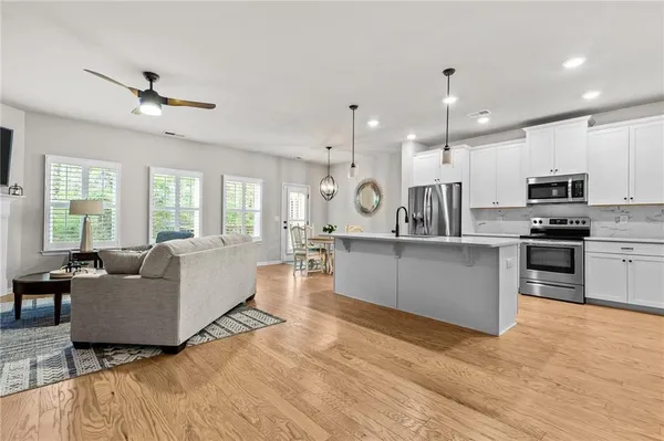 a large white kitchen with kitchen island a large counter top space a sink stainless steel appliances and cabinets