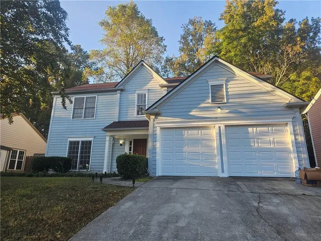 a view of house with a yard and large tree