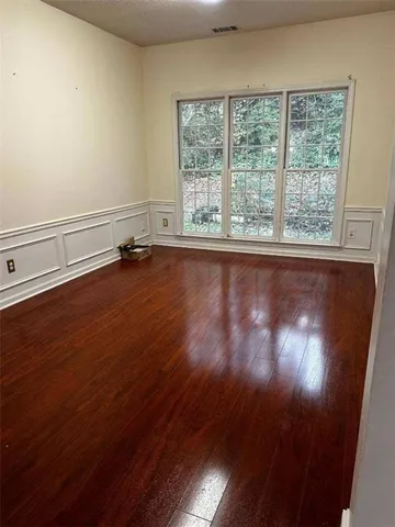 an empty room with wooden floor and windows