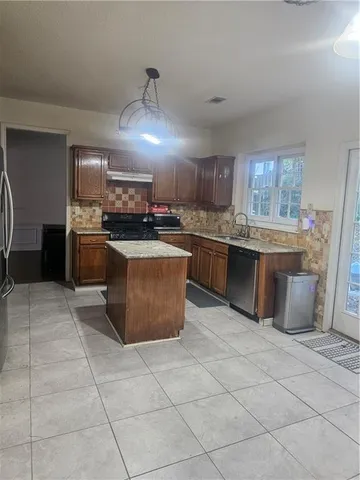 a large kitchen with granite countertop a stove top oven a sink dishwasher and a refrigerator