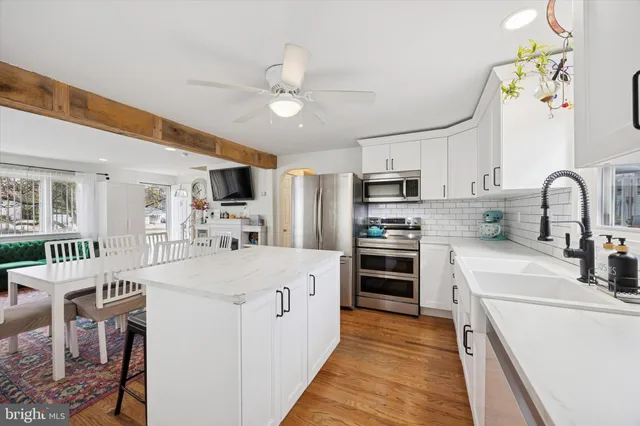 a large kitchen with stainless steel appliances granite countertop a stove oven a sink dishwasher a dining table and chairs with wooden floor