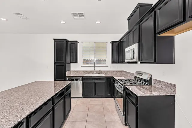a kitchen with stainless steel appliances granite countertop a sink stove and microwave