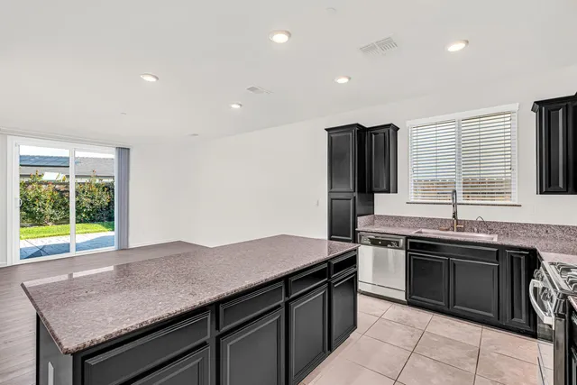 a kitchen with stainless steel appliances granite countertop a sink dishwasher stove and refrigerator