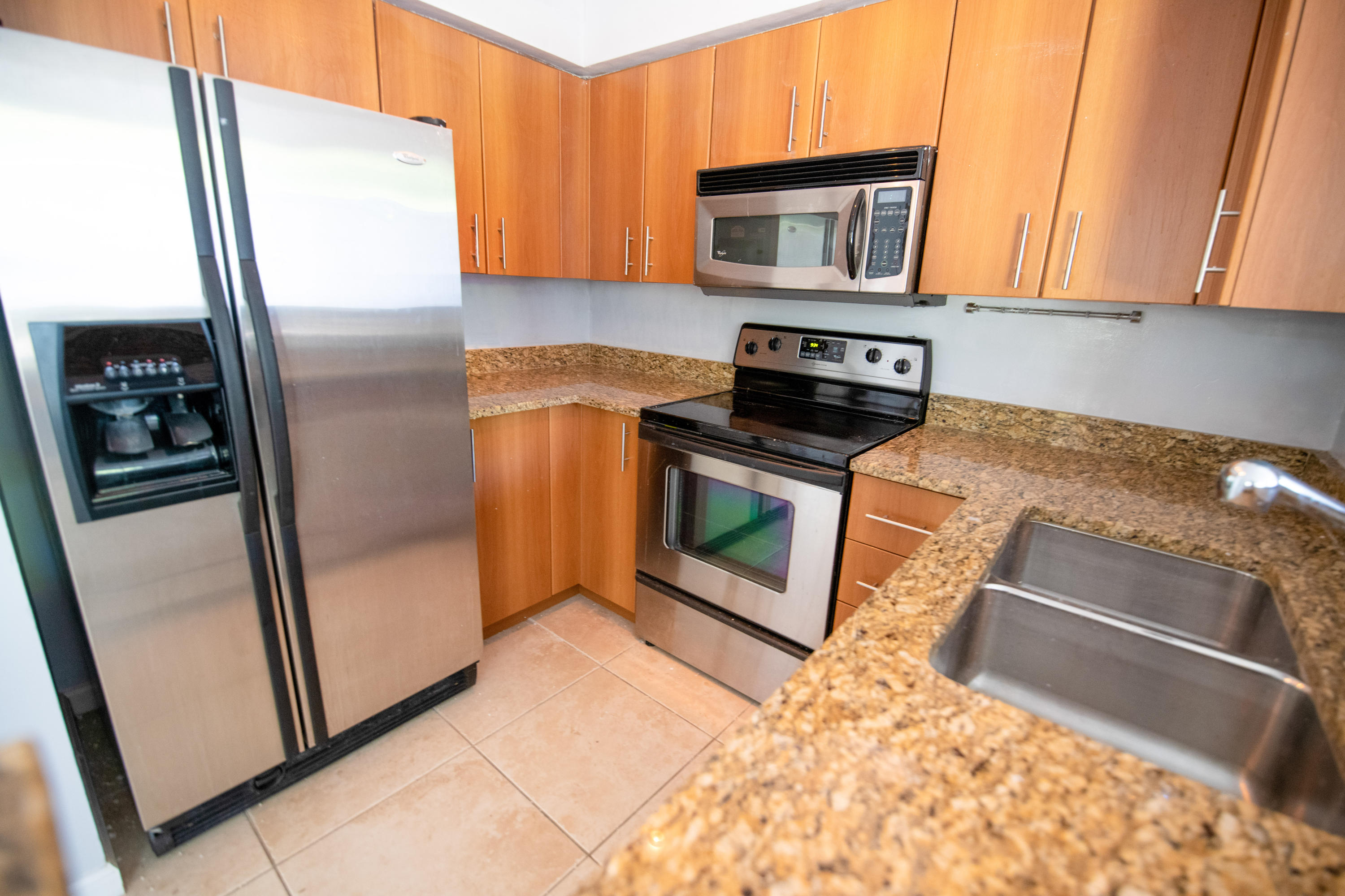 1165 Crystal Way, Unit B Delray Beach, FL 33444 - Photo 12 of 27 a kitchen with granite countertop a refrigerator stove and microwave